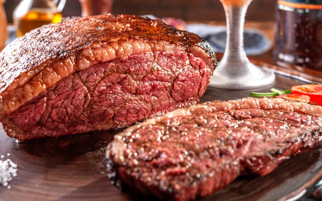 Bife grelhado suculento, servido em fatias e acompanhado de legumes frescos.